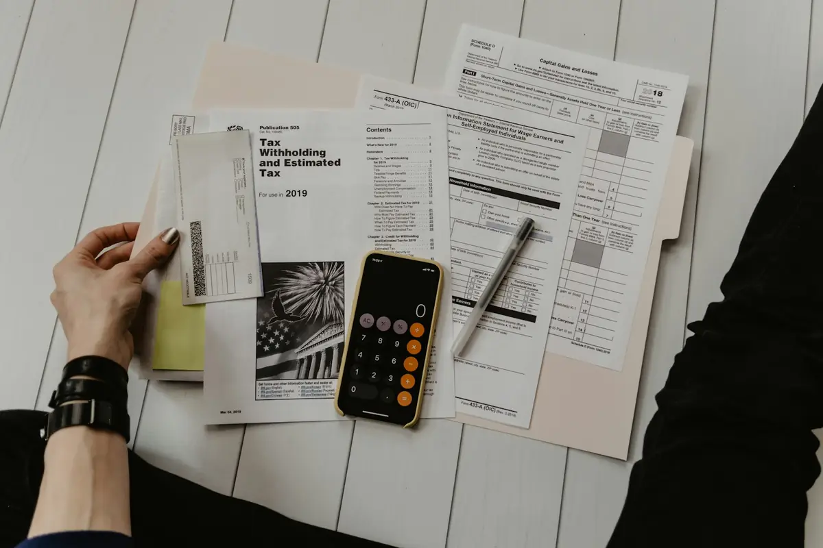 Tax forms, a calculator and a pen laid out on a desk